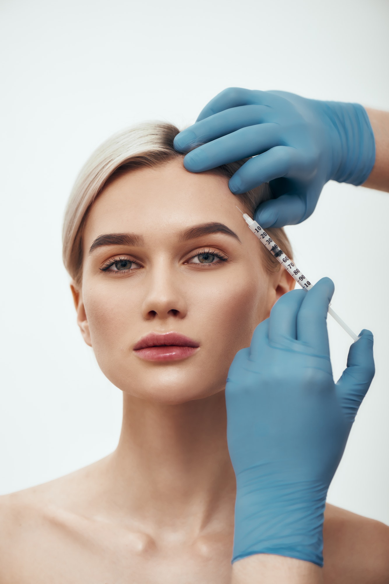 Portrait of young pretty woman looking at camera while doctors hand